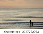 Mother and kid standing on the beach during sunset