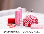 Small photo of Handmade and sewing background. Spool thread bobbins, pincushion, push pins, needles, scissors, buttons, sewing accessories for needlework on white wooden background. Sewing tools, supplies