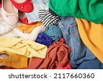 Small photo of Fast fashion background with pile of cheap, low quality clothes. Garment made in unjust, inhumane conditions idea. Environmental impact, carbon emissions concept