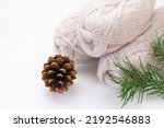 Balls of gray yarn, pinecone, spruce branch on a white background. Knitting, sewing, needlework, hobby, leisure. Copy space