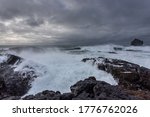 The harsh Icelandic coast with big waves beating against black rocks on a cloudy evening in the West of Iceland