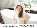 Portrait of a cute girl in a white coat with a unicorn in a bright bathroom with a window. Hygiene. Morning routine. Purity. High quality photo