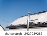 Small photo of chrome-plated chimney pipe, warm air exhaust outside, steel chimney on the roof of the house, snow-covered roof, chimney installation.