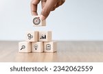 Small photo of Business success goals Concept. Hand holding target board which printing on wooden cube block for creative and set up business objective target goal concept, blocks to create ideas, set target.