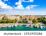Croatia, Istria, city of Pula, ancient Roman arena, historic amphitheater and harbor with ships from drone, aerial view