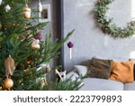 Close up of christmas tree with beautiful christmas decorations.  Christmas interior background with cozy sofa and pillows. Scandinavian style. Copy space. Selective focus.