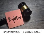 Small photo of Top view of gavel and sticky note with Bylaw wording over a wooden background with vintage effect. Law concept. Selective focus image