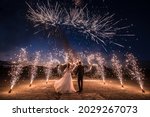 A couple in wedding dresses on the background of fireworks at night.