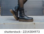high-soled leather black high-top lace-up boots with yellow stitching on a gray background