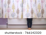 Young girl hiding behind a curtain with only her legs showing