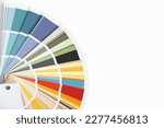 Small photo of Color guide close up. Assortment of colors for design. Colors palette fan on a white concrete wall background. Graphic designer chooses colors from the color palette guide. Coloured swatches catalogue