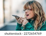 middle aged woman sending voice or audio message with mobile phone or smartphone
