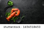 Boiled lobster with vegetables on a black stone plate. Seafood. Top view. Free space for your text.