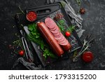 Salami with fresh rosemary and spices. on a black stone background. Top view. Free space for text.