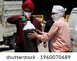 Small photo of New Delhi, India, April 21, 2021:A relatives carrying medical oxygen cylinder for Covid-19 infections patients at a gas supplier filling station during the second wave of coronavirus Covid-19 pandemic