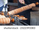 Trdelník is a kind of spit cake. It is made from rolled dough that is wrapped around a stick, then grilled and topped with sugar and walnut mix.