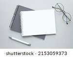 Business concept - Top view collection of grey notebook front, back pen, and white open page isolated on background for mockup