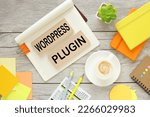 text on wooden blocks. cup of coffee, orange notepad, potted plant. WORD PRESS PLUGIN