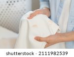 Small photo of Housewife, asian young woman hand in holding shirt, showing making stain, spot dirty or smudge on clothes, dirt stains for cleaning before washing, making household working at home. Laundry and maid.
