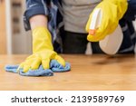 Cleaning hygiene, close up hand of maid, waitress woman wearing yellow protective gloves while cleaning on wood table, use blue rag wiping to dust and spray in restaurant. Housekeeping cleanup,cleaner