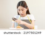 Small photo of Diet, attractive asian young woman, girl restrained to eat doughnut, bakery and fried chicken, fast food to lose, loss weight, hugging weight scales on table at home. Passion, temptation when hungry.