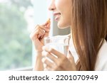 Small photo of Dietary supplement, asian young woman, girl hand holding orange medical pill, take or eat vitamin C, D for treatment for skin, hair and nail strengthen with glass of pure water at home, healthcare.
