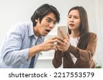 Small photo of Infidelity, suspicion asian young couple love fight relationship, wife holding cellphone, smartphone cheating on phone, scolding husband about mistrust, distrust and jealousy at home.