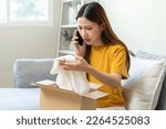 Small photo of Angry bad, complaint asian young woman opening carton box, received online shopping parcel wrong product order from retail store, using mobile phone talking with support shop want to return package.