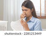 Small photo of Asian young housewife woman having bad smelling clothes holding breath nose with fingers, sniff smelly dirty stinky musty, look disgusting from clothes after washed clothes, laundry out of machine.