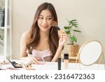 Small photo of Happy beauty blogger concept, cute asian young woman, girl smile, make up face by applying brush blush powder on her cheek, looking at the mirror. People look with natural fashion style.