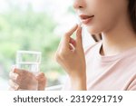 Small photo of Dietary supplement asian young woman hand holding medical pill capsule, take or eat vitamin in mouth for treatment, sick female taking medicines drinking with water at home, pharmacy and healthcare.