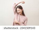 Small photo of Bad smelling, deodorant asian young woman smell stink, breathing nose on armpit with underarm, smelly shirt dirty stinky laundry, disgusting from clothes after washed. Medical health, skin body care.
