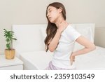 Small photo of Pain body muscles stiff problem, asian young woman painful with back, neck ache from work hand holding massaging rubbing shoulder hurt, sore sitting on bed in room at home. Health care and medicine.