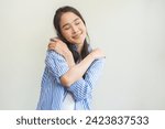 Small photo of Smiling positive, hug self care happy asian young woman hands hugging herself shoulders, enjoy yourself, self love and self care, smile girl face expression self esteem standing isolated on background