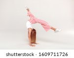 Small photo of Red-haired girl isolated on grey background inclusive beauty standing on hands doing front handspring