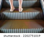 Women's legs standing on escalators stairway.