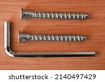 Small photo of hex bolts, screws with hex key, close-up of bolt heads, hex wrench, hex head screws thread, wooden background, top view. macro.