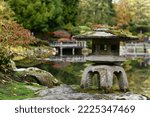 Background with japanese traditional old stone lantern near the lake in the Japanese garden.  Japanese lantern with moss in Japanese garden, Seattle. 