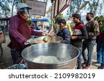 Small photo of Ghaziabad, Uttar Pradesh, India-Jan 19 2022: A volunteer serving food to poor people. A food center run by charitable trust, they charge 5 Indian Rupees for per plate of food.