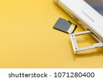 Flash memory data storage concept : A tray with a micro SD card on yellow background. A memory card is used for storing digital information in portable electronic devices e.g mobile phone, tablets etc