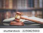 Legal office of lawyers, justice and law concept : Judge's gavel or hammer and base used by a judge person on a desk in a courtroom with blurred books and a bookshelf or bookcase in the background.
