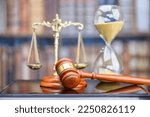 Legal office of lawyers, justice and law concept : Judge's gavel or hammer and base used by a judge person on a desk in a courtroom with blurred weight scale of justice, bookshelf, hourglass behind.