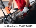 Small photo of Auto specialist worker hand blowing hot air dryer or hairdryer removing old car window film tint and installing the new one. Car front windscreen film removal and tinting installation