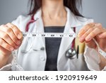 Small photo of Close up isolated image of a caucasian doctor holding a tape measure in her hands which shows 40 inches as abdominal circumference upper limit in healthy people. Concept for weigh loss and fitness.