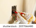 Small photo of An electrician is replacing a wall switch. A DIY project concept. High voltage danger. The professional wearing shock proof gloves is tightening wirenuts