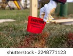 Small photo of Concept image for 811 call before you dig service. Utility companies come and mark the places of buried cable tv, water, electric and gas lines using color coded spray paint and pin flags.