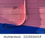 Urban cable plastic flexible conduit painted pink on funky wall background 