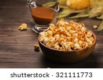 Wooden bowl full of sweet caramel popcorn with caramel sauce and corncobs over rustic table. Vintage style. Selective focus