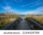 Pathway to the beach between sand dunes. Wooden path over dunes leading to the ocean. Jacksonville, Florida, USA.
