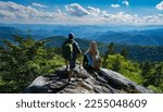 Small photo of People relaxing on hiking trip. Couple on top of the mountain enjoying beautiful view. Blue Ridge Mountains, near Asheville, North Carolina.USA.
